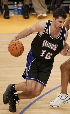 European Players photo of Peaj Stojakovic in action on court, running with the ball in left hand, pushing away opponent on right
